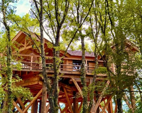 a tree house with a wrap around deck in the trees at Dolce et Cabane in Bérat