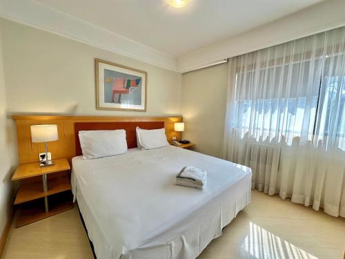 a bedroom with a large white bed and a window at Bienal First Class Flat Service in São Paulo