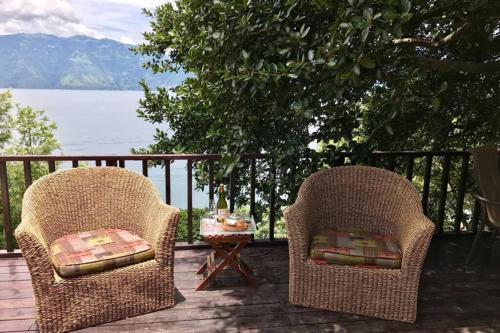 two wicker chairs sitting on a deck with a table at Beautiful Lake Front House AT001 in Sololá