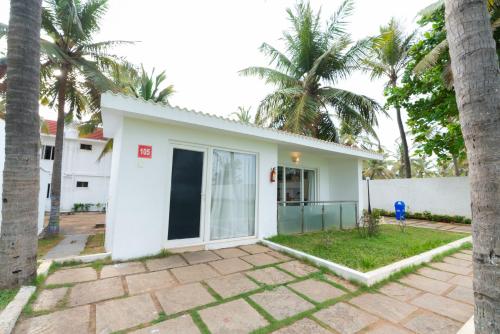 a white house with palm trees in front of it at Shelter Beach Resort in Mahabalipuram