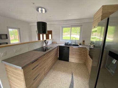 une cuisine avec des armoires en bois et un réfrigérateur noir dans l'établissement Chalet au calme avec vue, à Viéville