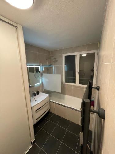 La salle de bains est pourvue d'un lavabo blanc et d'une baignoire. dans l'établissement Appartement Cosy Balcon Parking, à Chazay-dʼAzergues