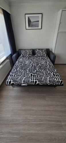 a bed with a black and white comforter in a bedroom at Studio Casa Brisa Del Mar in Middelkerke