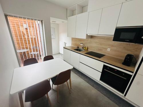 a kitchen with white cabinets and a table and chairs at Woning Meningate in Ypres