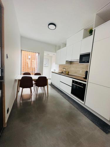 a kitchen with white cabinets and a table and chairs at Woning Meningate in Ypres