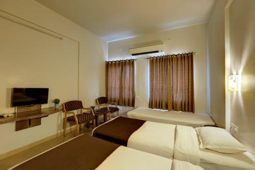 a hotel room with two beds and a television at Hotel Orient Crown, Kolhapur in Kolhapur