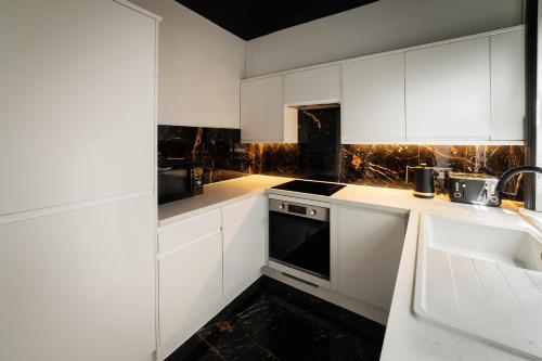 a kitchen with white cabinets and a sink at Casa Amor - Adult Only Retreat Midlands in Stoke on Trent