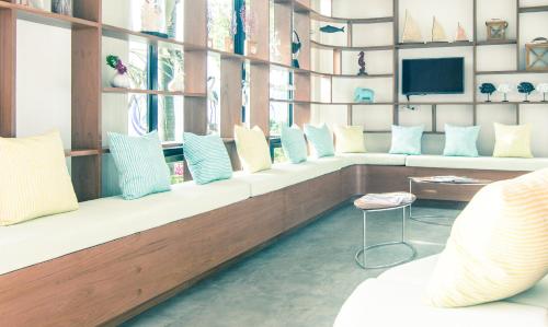 a room with a long bench with pillows and a tv at The Phu Beach Hotel - SHA Plus in Ao Nang Beach