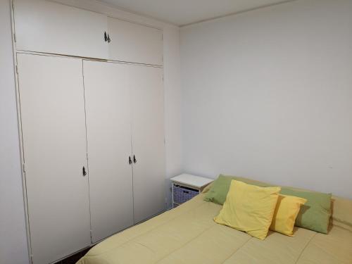 1 dormitorio con armarios blancos y 1 cama con almohadas amarillas en Casa Anne, en Tandil