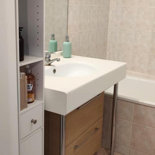 une salle de bain avec un lavabo blanc et une baignoire dans l'établissement Lush Fresh Home in Paris near Stade de France, à Saint-Denis