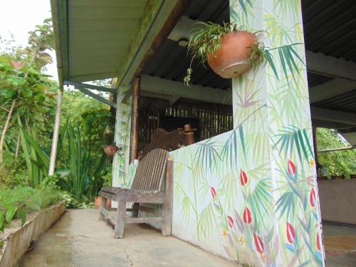 a bench on a porch with a plant on a wall at Dunarinka in Minca