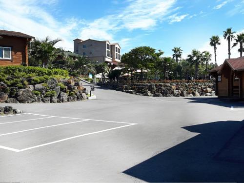 a parking lot with a tennis court in front of a building at Jeju I've Hotel & Resort in Seogwipo