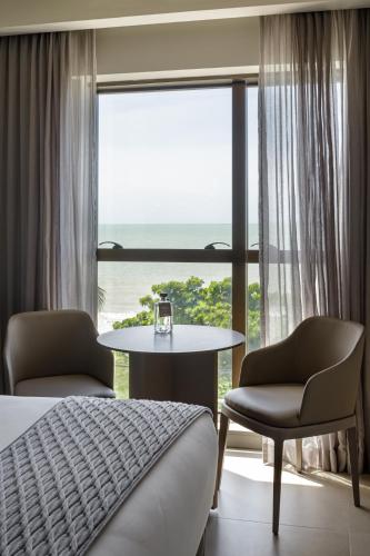 a hotel room with a bed and a table and a window at HCM - Hotel Corais de Manaira in João Pessoa