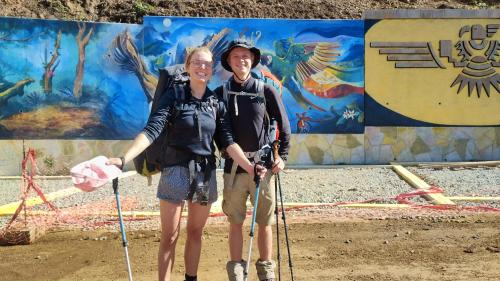 two people are posing for a picture in front of a wall at the wooden house choquequirao in Cachora