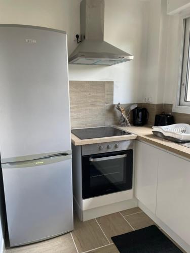 a white kitchen with a stove and a refrigerator at Appart 4 personnes 1 ch Laval in Laval