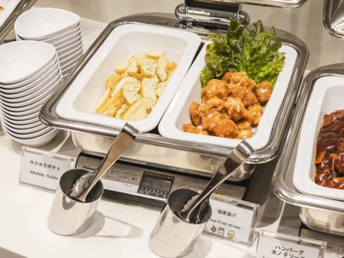 a buffet with two trays of food and spoons at Sotetsu Fresa Inn Hiroshima in Hiroshima