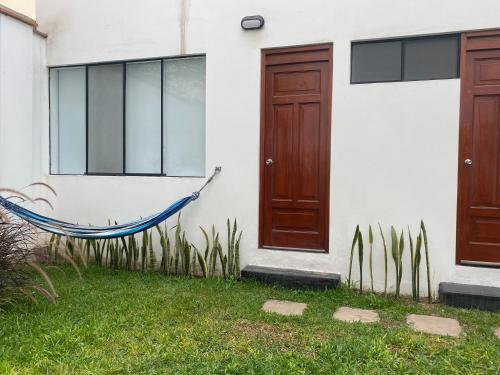 a hammock in front of a house with two doors at Hermosa habitación independiente cerca a Miraflores in Lima