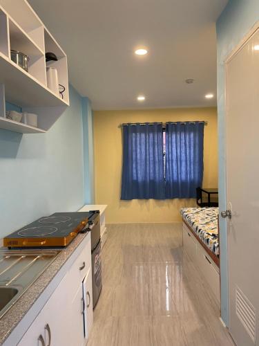 a room with a kitchen with a bed and a window at LL-Apartelle in Lo-oc