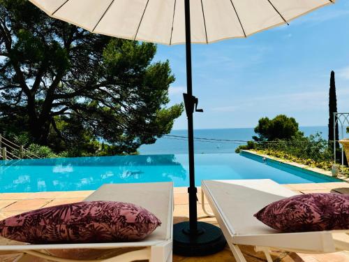 une table et des chaises avec un parasol à côté d'une piscine dans l'établissement L'équinoxe vue sur la mer, à Sète