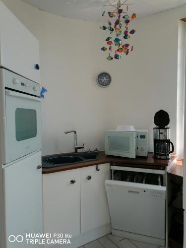 une cuisine avec des armoires blanches et un micro-ondes dans l'établissement Château de chimay, à Barneville-Carteret