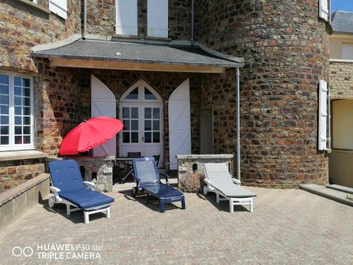 - un ensemble de chaises et un parasol rouge sur la terrasse dans l'établissement Château de chimay, à Barneville-Carteret
