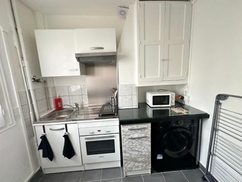 une petite cuisine avec des armoires blanches et un micro-ondes dans l'établissement Apart 2piece 4 personnes, à Saint-Ouen