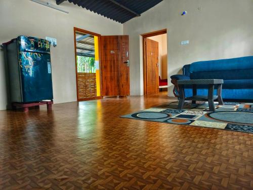 un soggiorno con un divano blu e un tavolo di Private Villa Inside Coconut Farm By Shivalaya ad Alāndurai