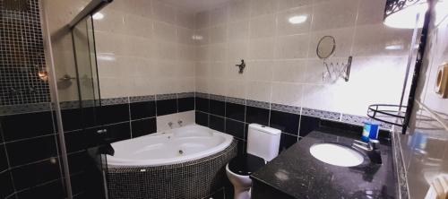 a bathroom with a sink and a toilet and a shower at Hotel Pousada Viking in Jacumã