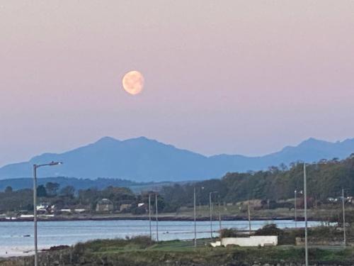 a moon in the sky over a body of water at New 2 bed Lodge near Dunoon on the Shore Front in Dunoon