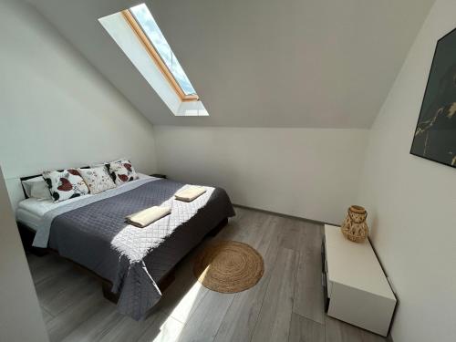 a small bedroom with a bed and a skylight at Koniec Świata Stare Sady apartament in Mikołajki