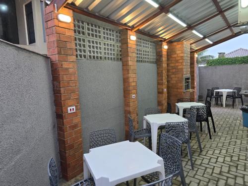 a patio with white tables and chairs and a brick wall at Triplex de veraneio em Guaratuba in Guaratuba