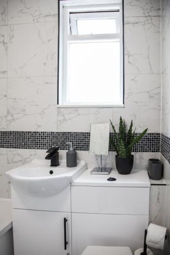 a white bathroom with a sink and a window at Spacious House 10min to Liverpool Centre in Wallasey