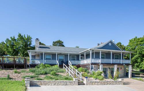 une maison bleue avec un porche et une terrasse dans l'établissement Large patio and hot tub near wine country, à Fredericksburg