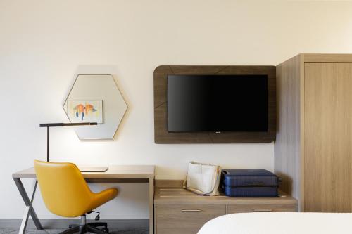 a room with a desk and a tv and a yellow chair at Holiday Inn Express Williamston by IHG in Williamston