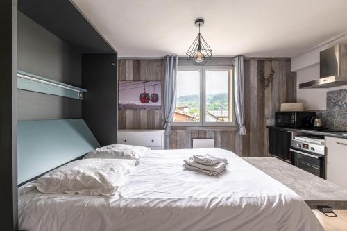 a bedroom with a large white bed with a window at Appartements vue Mont-Joly à 2 pas Tramway Mont-Blanc - Studio 1 pièce in Saint-Gervais-les-Bains