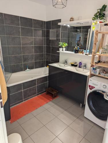 La salle de bains est pourvue d'une baignoire, d'un lavabo et d'un lave-linge. dans l'établissement Aux pieds des dunes, à Labenne