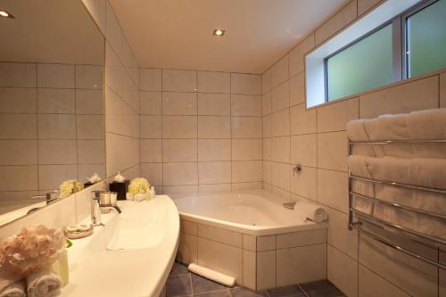 baño con bañera, lavabo y ventana en Highview Terrace by Amazing Accom, en Queenstown
