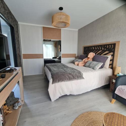 a bedroom with a large bed with a teddy bear on it at Joli Appartement de plain-pied in Pornic
