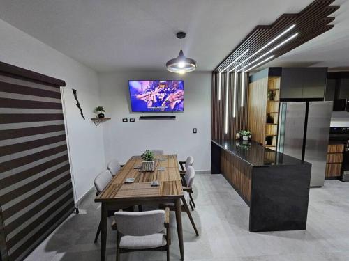 a dining room with a table and a tv on the wall at Casa Angulo 8 Guest Gated Home in Viñedos Del Mar in El Suazal