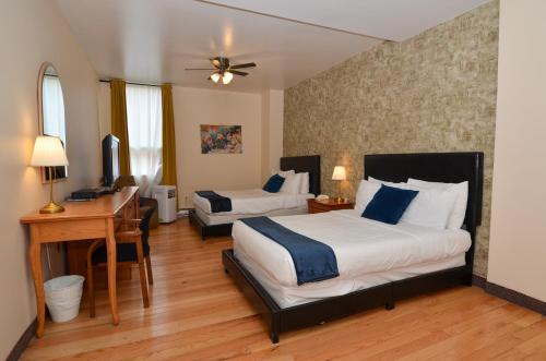 a hotel room with two beds and a desk and a desk at Hotel Dorion in Montréal