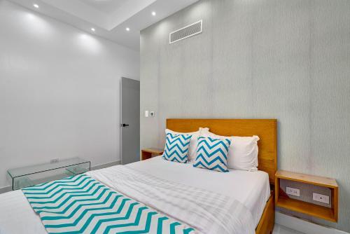 a bedroom with a large bed with blue and white pillows at Monaco Residences Piantini in Santo Domingo
