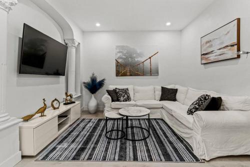 a living room with a white couch and a tv at Appartement haut de gamme NDG in Montréal