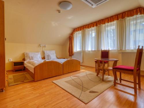 a bedroom with a bed and a table and a chair at Villa Park Apartmanház in Szilvásvárad
