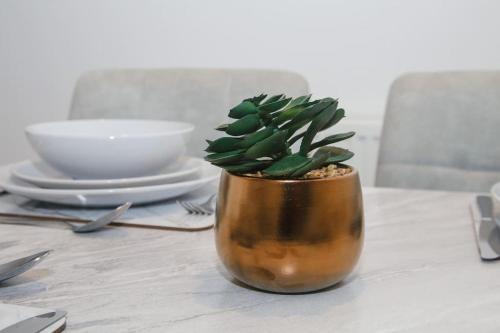 un vase avec une plante assise sur une table dans l'établissement Homely 3-bed home Milton Keynes, à Simpson