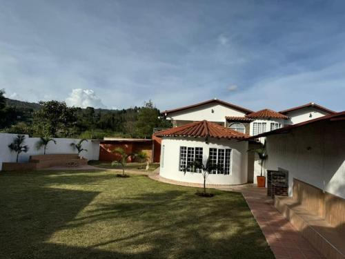a yard with a white house with a grass yard at Hermosa cabaña en Guarne in Copacabana