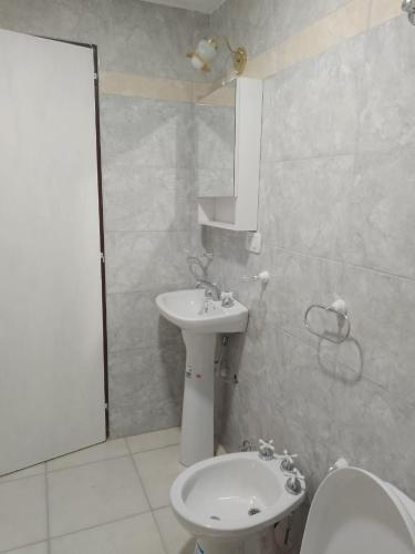 a white bathroom with a sink and a toilet at Departamento Lucia in Trelew