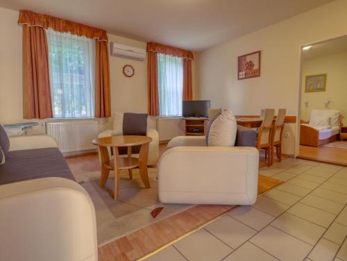 a living room with white furniture and a table at Villa Park Apartmanház in Szilvásvárad