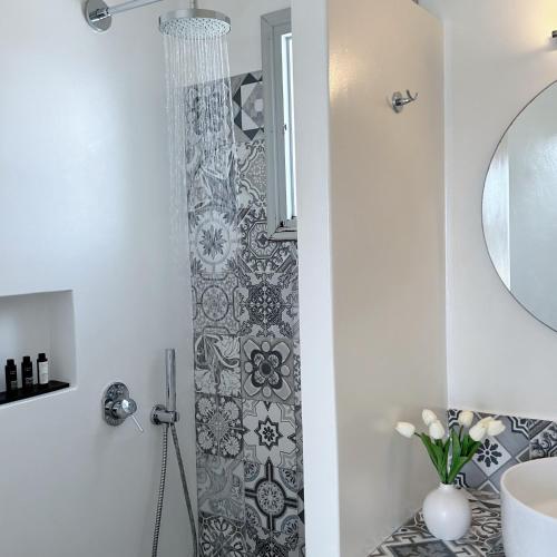 a bathroom with a shower with a sink and a mirror at Anita Rooms & Suites Milos in Adamas