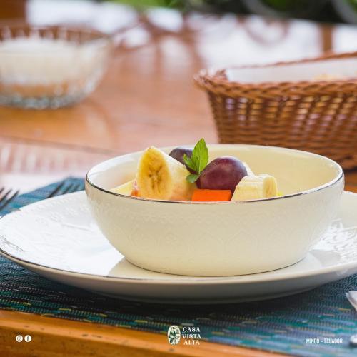 a white bowl of fruit and vegetables on a plate at Casa de Vista Alta in Mindo