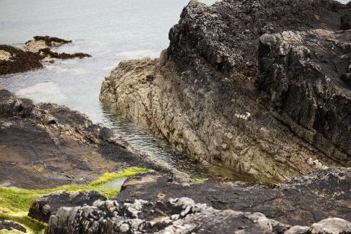 a rocky shoreline with a body of water at Pierside Apartments Deluxe Accommodation in Portsalon